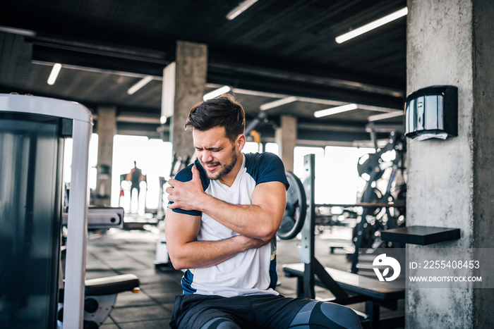 Portrait of a handsome man with strong facial expresion and injured arm while exercising in the gym.