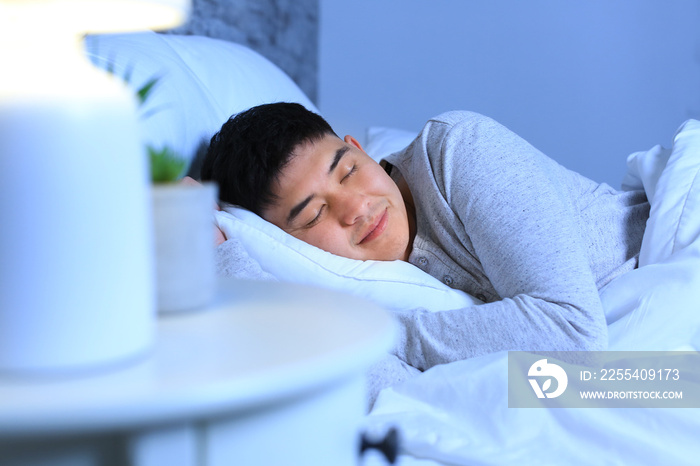 Asian man sleeping in bed at night