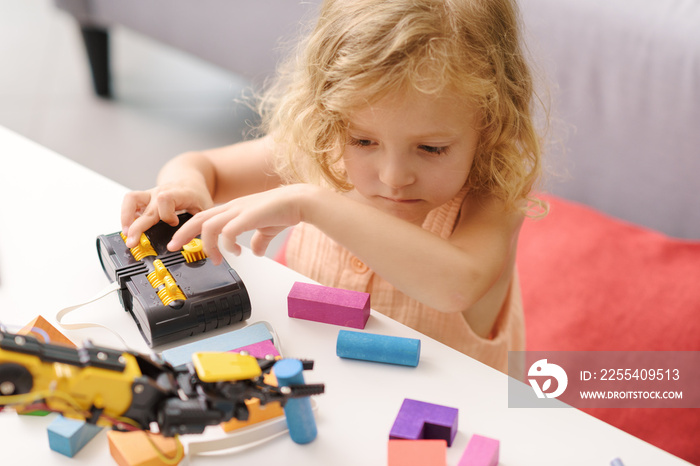 Cute girl playing with a robotic arm toy