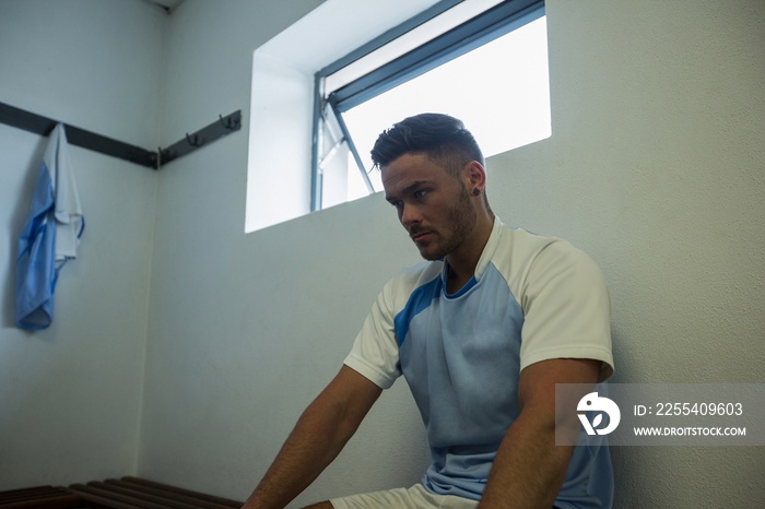 Football player sitting on bench in changing room