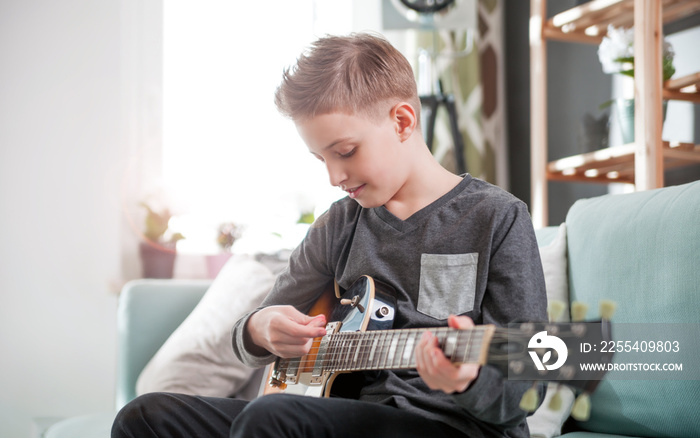 Young boy playing electric guitar at home