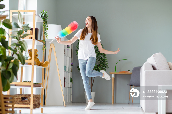 Full length body size view of attractive cheerful carefree girl dancing singing in fluffy brush having fun at home living room indoors