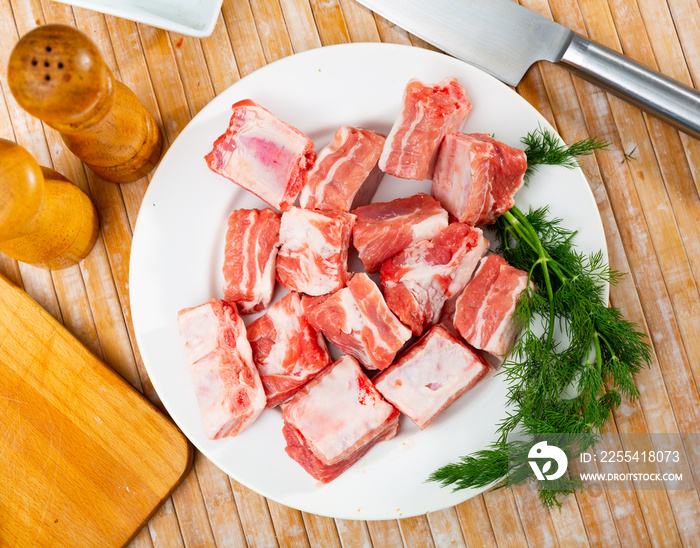 Chopped raw pork ribs placed on table with dill.