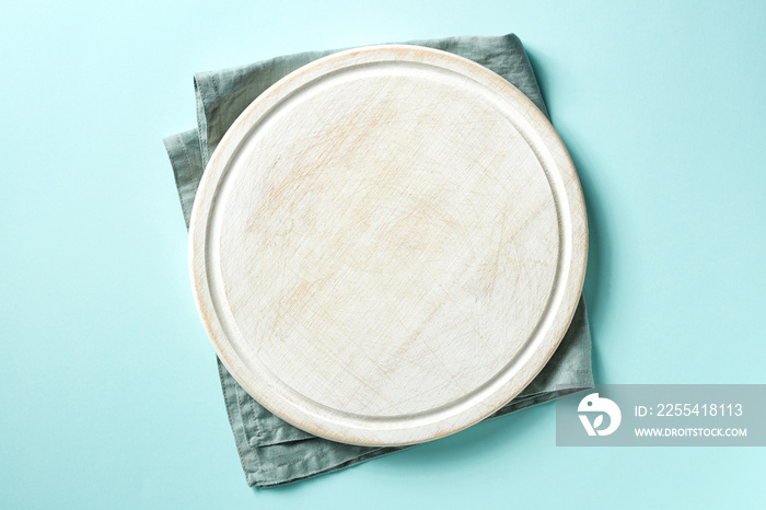 Wooden cutting board on blue background, from above