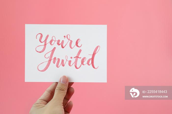 Hand holding card with text  You’re Invited