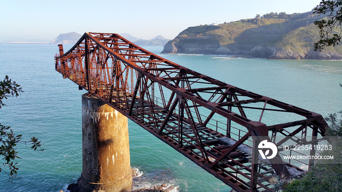 Bridge to nowhere. Abandoned overpass for loading ore from an old mine on the seashore. View from above, against the background of the sea. Miono, Cantabria, North spain.