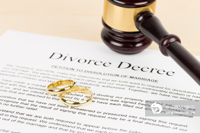 Wooden judge gavel, golden rings, and divorce decree; document is mock-up