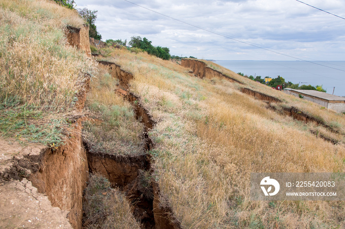 landslide in an environmentally hazardous area slopes on the coast, large crack in ground descent of large layers of soil.