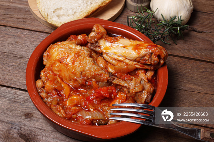 Delizioso pollo alla cacciatora in una ciotola su fondale di legno rustico.