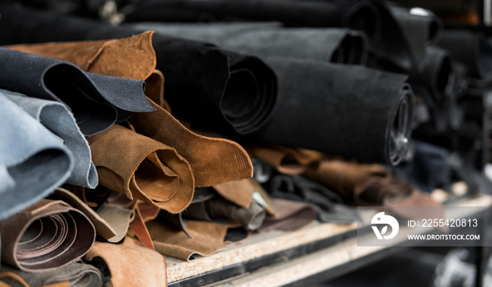 Different pieces of leather in a rolls. The pieces of the colored leathers. Rolls of natural brown and black and other leather. Raw materials for manufacture of bags, shoes, clothing and accessories.