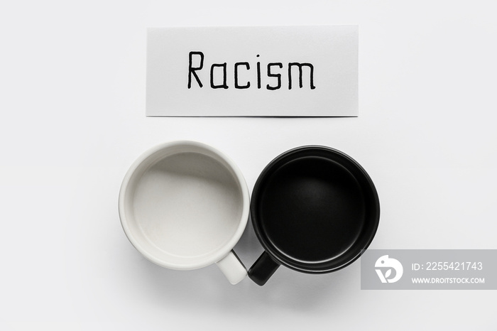 Paper piece with word RACISM and cups on white background