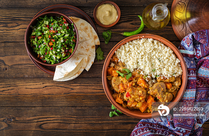 Traditional tajine dishes, couscous  and fresh salad  on rustic wooden table. Tagine lamb meat and pumpkin. Top view. Flat lay