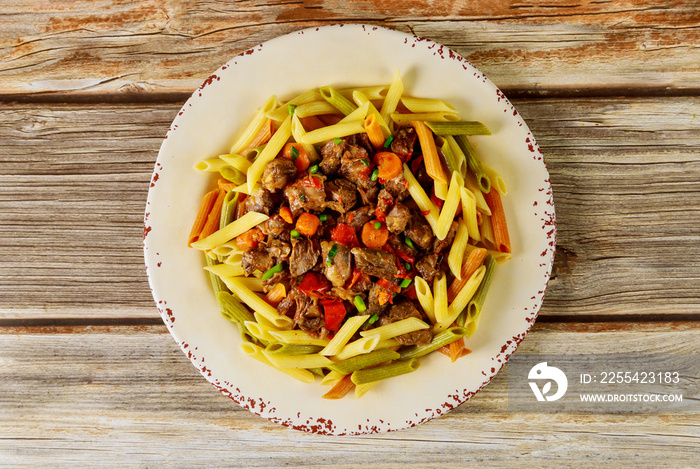 Color penne pasta with meat in sauce and vegetables