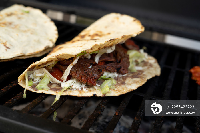 top view of Mexican food Tlayuda de cecina y chorizo and its preparation ingredients on a wooden table, frijoles, beans, cecina, sausage, lettuce, sauce, fruit water