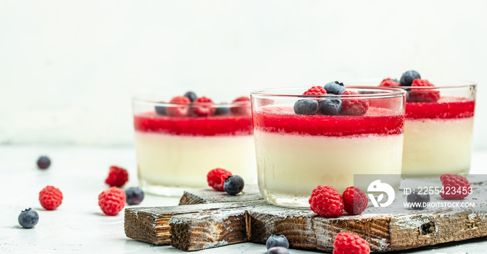 Italian dessert. Raspberry Panna cotta with raspberry jelly on a light background. Berry dessert with cream sauce in small jars. Long banner format. place for text