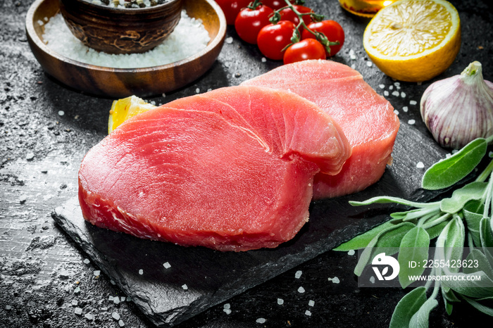 Raw tuna fillet on a stone Board with salvia and lemon.