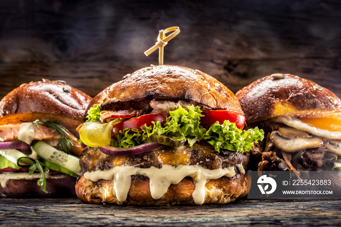 Front view on three large, beef salmon and kebab burgers stuffed with fresh vegetable salad and dressing