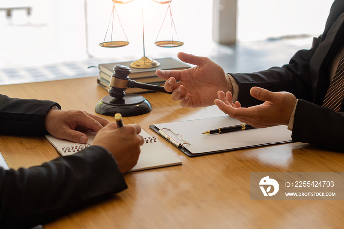 Businessman and lawyer discussing contract documents sitting at a table Legal ideas, advice, agreements with a partner attorney or lawyer discussing contractual agreements.