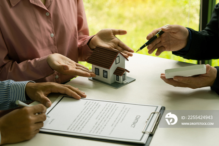 Real estate professionals and clients discussing home purchases, insurance or real estate loans. Home sales agents sit at the office with new homebuyers in the office.