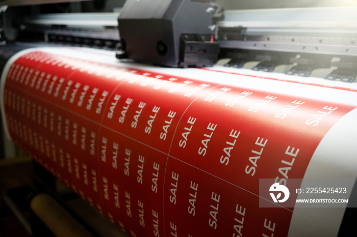 Printing a banner with the inscription sale on the printing press. Large-format printing in production. Stickers are on sale for Black Friday.