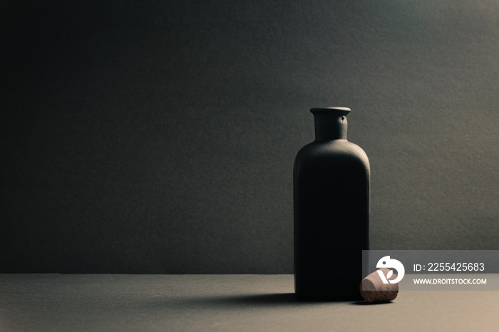 Single black ceramic bottle with the plug off over a dark background