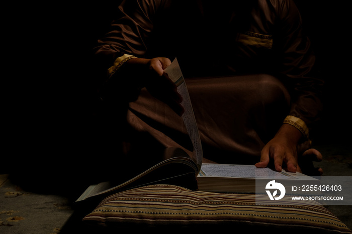 Selective focus picture men turning Quran page in dark mood. Quran hour concept