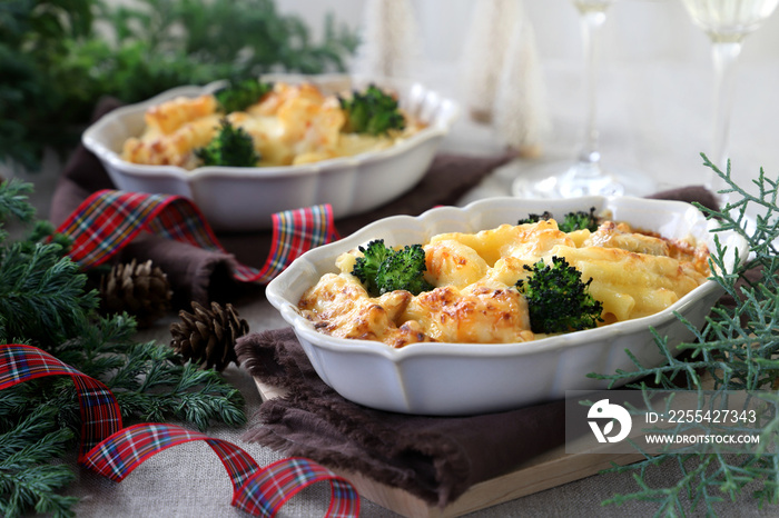 Homemade gratin with shrimp and cheese in baking dishes on Christmas decoration table.　マカロニグラタン