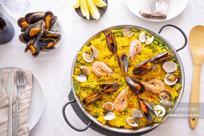 Top view of Seafood Paella with  prawns, clams, mussels on saffron rice and vegetables served in  traditional frying pan on the table.