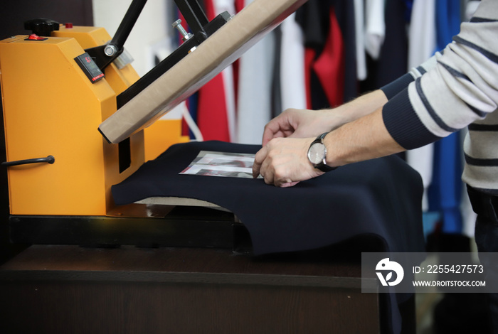 Man preparing t-shirt for printing in the silk screen printing machine. Only hands