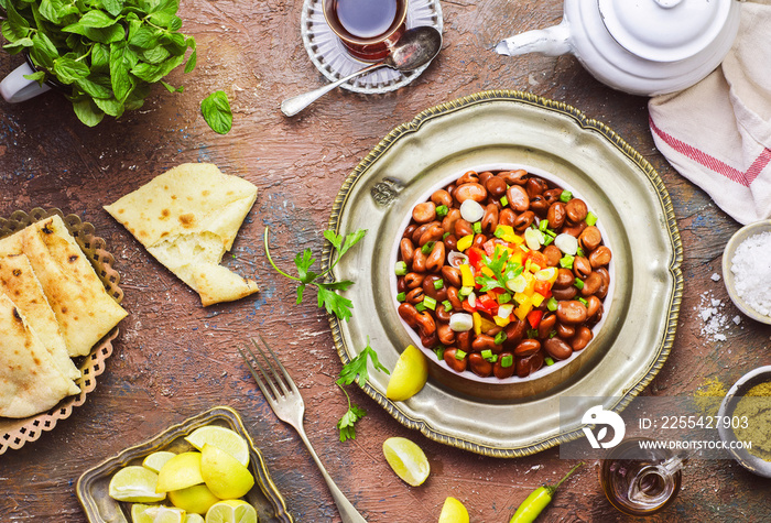 Arabic cuisine; Egyptian traditional dish  Ful Medames .Middle Eastern delicious breakfast with cooked Fava beans. Served with lemon, cumin, olive oil, salt, pita bread, cup of tea and fresh mint.