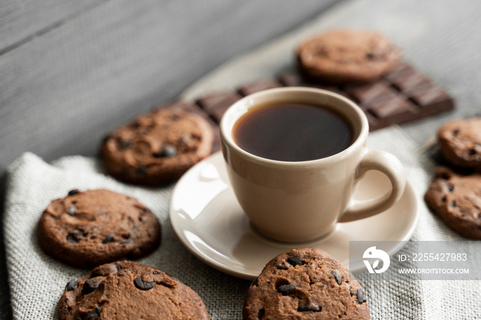 Coffee cup with cookies and chocolate on wooden table background. Mug of black coffee with chocolate cookies. Fresh coffee beans.