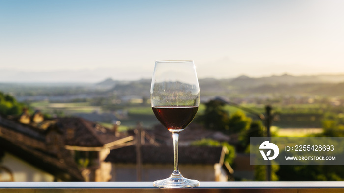 Single wine glass above vineyards, Piedmont, Italy