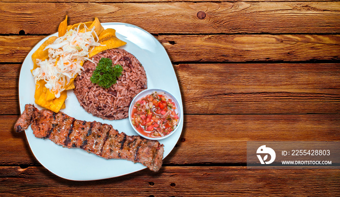 Roast beef with gallo pinto and pico de gallo, Nicaraguan food served on wooden table, Plate with roast beef and rice served on wooden table