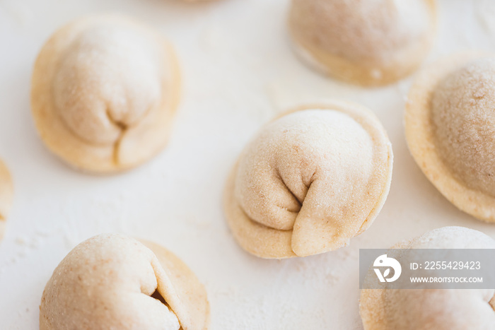 Uncooked homemade pelmeni on white table. Process of making pelmeni, ravioli or dumplings with meat