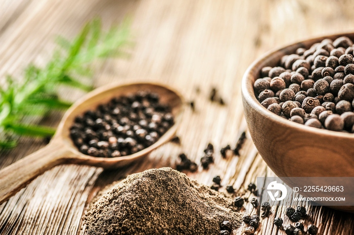 Black pepper in bow on wooden table. Pile of ground black pepper.