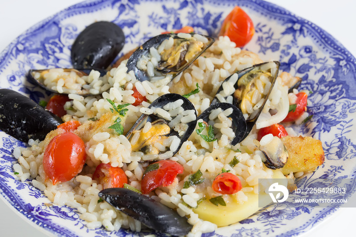 Rice, potatoes and mussels, traditional apulian dish, italian cuisine, Bari, close up on the color blue plate