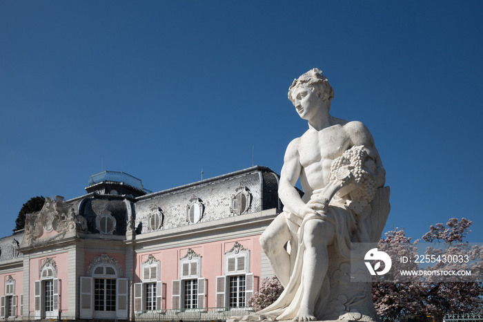 Selective focus at white classical male human sculpture and background of Schloss Benrath, old classic residence palace.