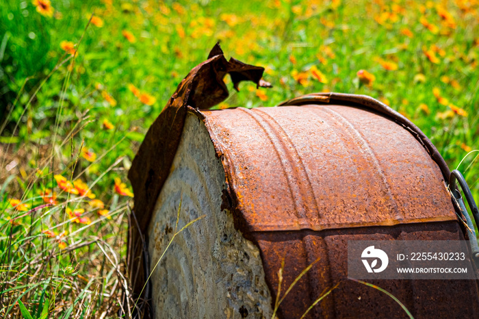 Rusty metal barrel in a field of wildflowers