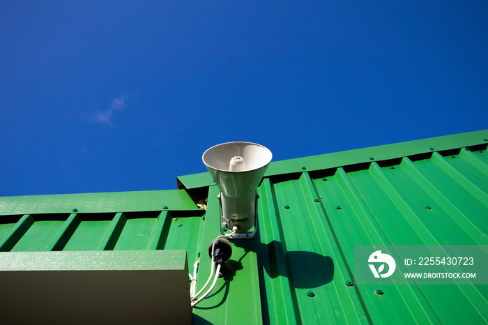 PA public address system speaker fixed to profiled metal clad building