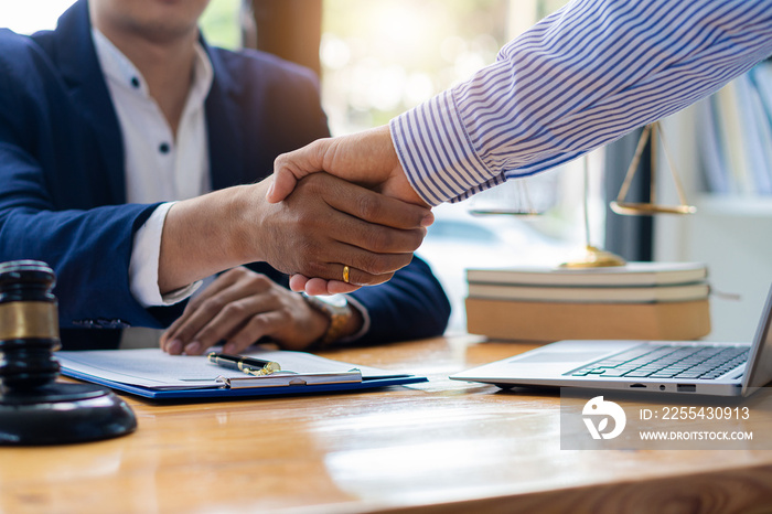 Picture of a businessman lawyer shaking hands with documents, contracts, client cooperation agreements, and hammers at the tables of a tax advisory and real estate concept company.