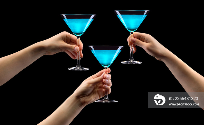 Set of hands holding blue martini glass isolated on black.