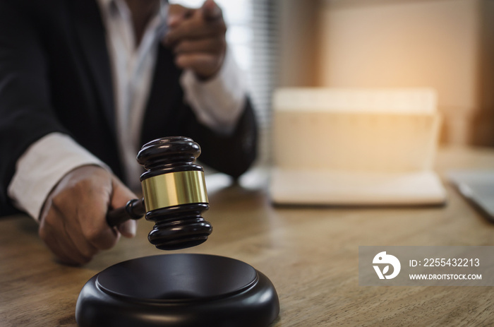 justice lawyer in black suit pointing finger and knocking wooden judge gavel with documents on workplace desk in courtroom office, occupation, business, justice law and legal service concept