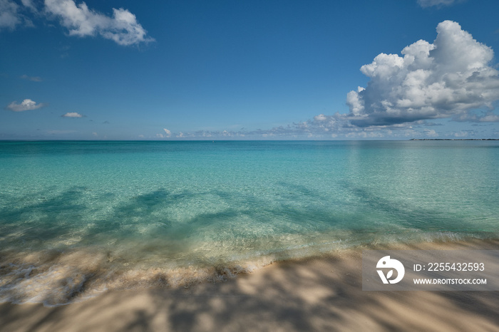 Crystal clear waters and pinkish sands on empty seven mile beach on tropical carribean Grand Cayman Island