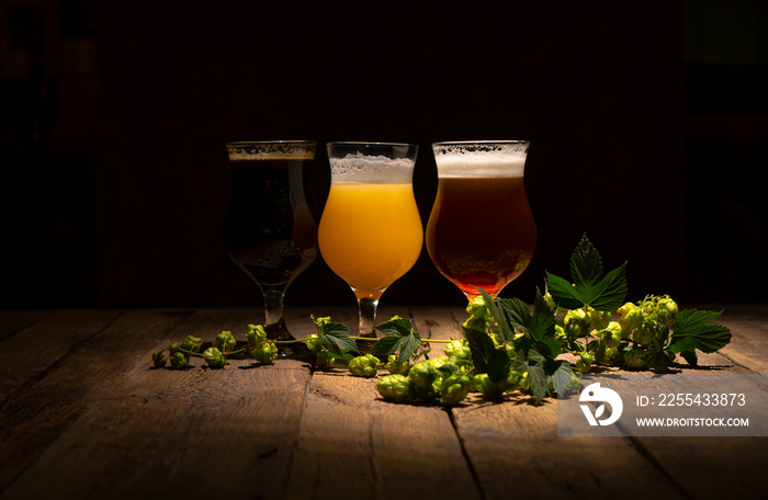 Beer glasses and hop branch on the rustic wooden table