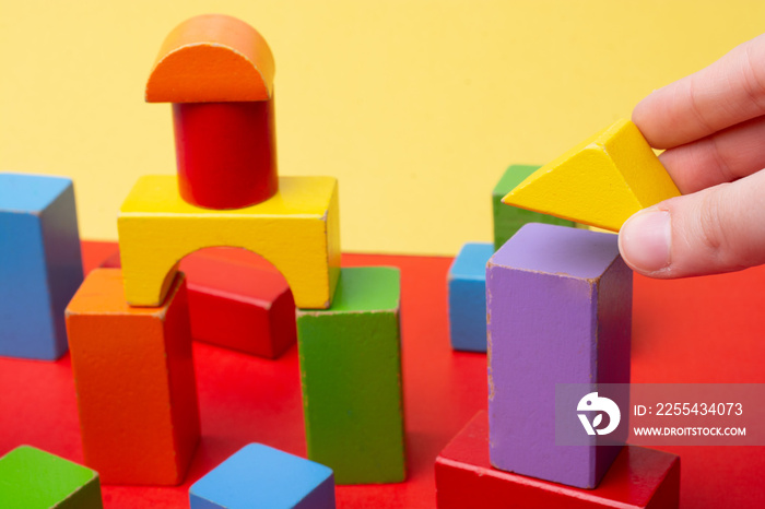 Hand playing with colorful toy blocks. Educational and creative toys