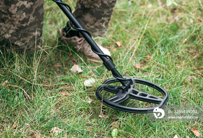 Soldier using a metal detector in fields. Ukrainian Explosive Ordnance Disposal Officer detecting metal by metal detector device