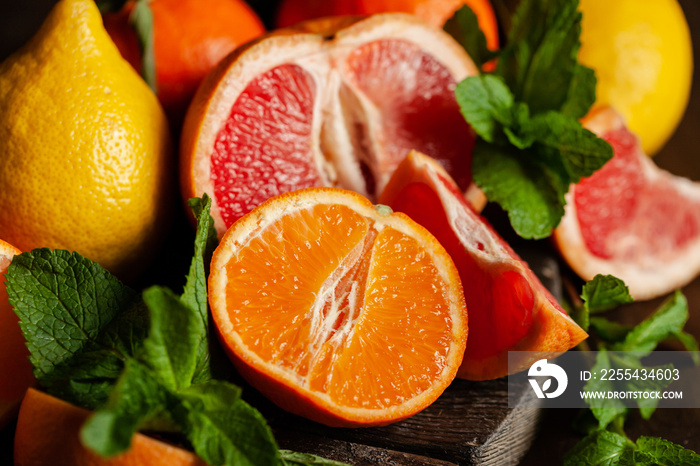 Slices of ripe fresh organic citrus fruits: grapefruit, orange, lemon on wooden board. Natural source of vitamins, low calories tasty dessert. Dark background, close up, front view