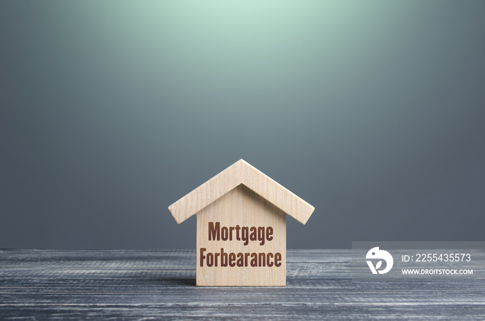 Wooden house figurine with inscription Mortgage forbearance. Borrower and lender agreements reduce or suspend mortgage loan payments for period of time. Financial relief measures. Prolongation