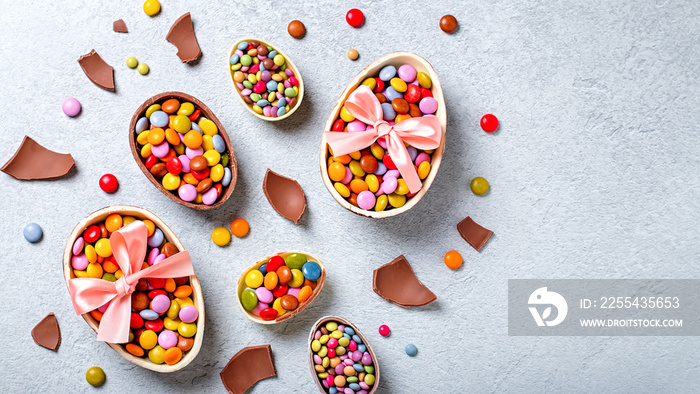 Chocolate Easter eggs and candy on concrete table, festive Easter background flat lay, copy space. Easter card with traditional Easter treats on grey table top. Sweet Easter concept