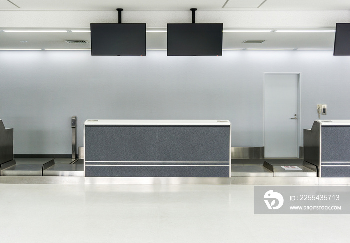 Empty desk in international airport at check-in counter with loading baggage area on background.